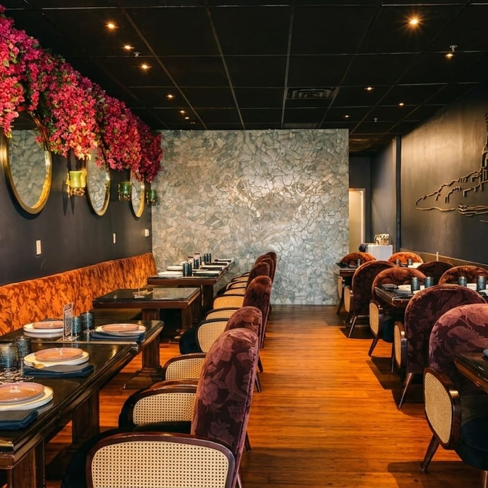 Elegant restaurant interior with dark walls, floral decor, and set tables with plush seating.